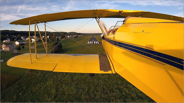Yellow Airplane Flying Toward Runway