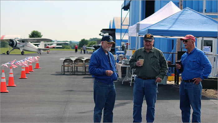 Three Men Talking Near the Airplane Hanger